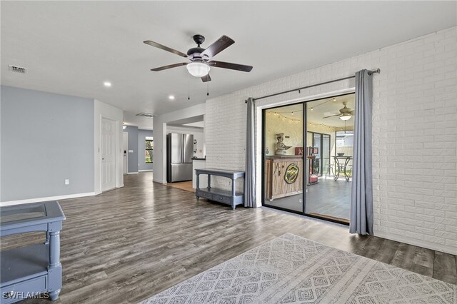 living room featuring wood-type flooring, brick wall, and ceiling fan