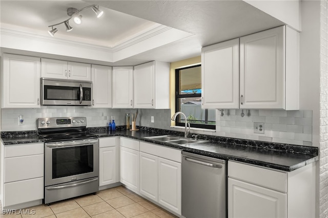 kitchen featuring sink, light tile patterned floors, crown molding, white cabinetry, and appliances with stainless steel finishes