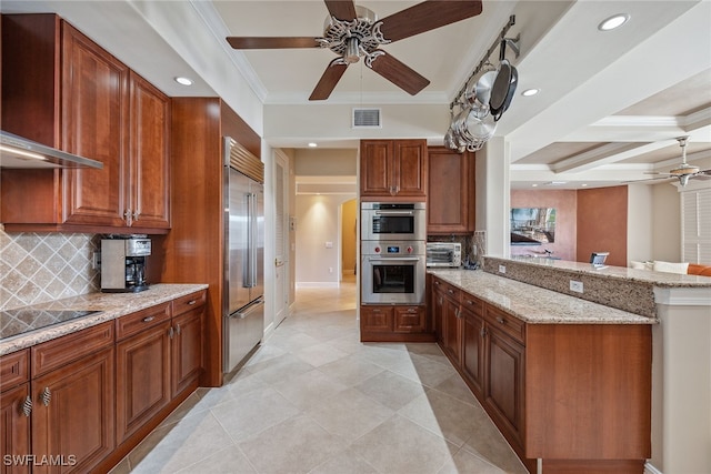 kitchen featuring stainless steel appliances, light stone counters, kitchen peninsula, tasteful backsplash, and wall chimney range hood