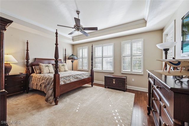 bedroom featuring hardwood / wood-style flooring, ceiling fan, crown molding, and a tray ceiling