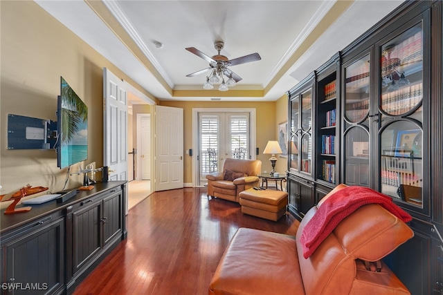 living area with ceiling fan, crown molding, dark hardwood / wood-style floors, and a raised ceiling