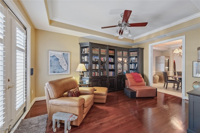 sitting room featuring a tray ceiling, ceiling fan with notable chandelier, dark hardwood / wood-style floors, and crown molding