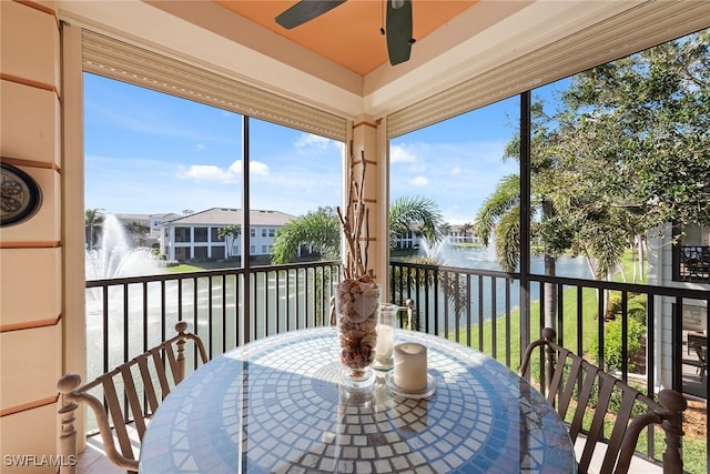 sunroom featuring a water view and ceiling fan