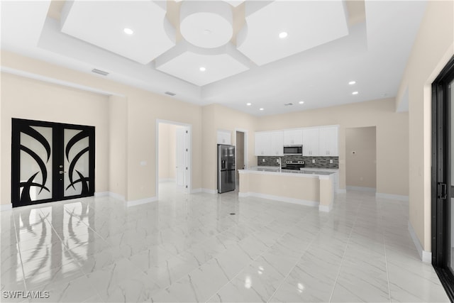 kitchen with sink, an island with sink, tasteful backsplash, white cabinetry, and stainless steel appliances