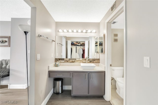 bathroom featuring vanity, toilet, a textured ceiling, and hardwood / wood-style floors