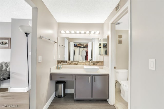 bathroom with toilet, baseboards, visible vents, and vanity