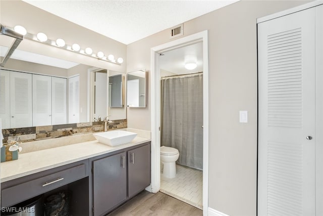 bathroom featuring toilet, hardwood / wood-style floors, vanity, and a textured ceiling