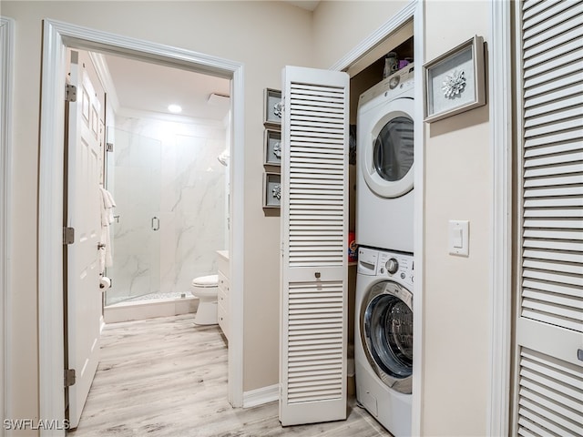 clothes washing area featuring light hardwood / wood-style floors and stacked washer and dryer