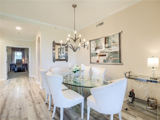 dining space with hardwood / wood-style flooring, ornamental molding, and an inviting chandelier