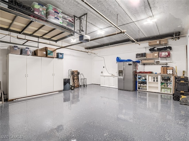 garage with stainless steel fridge with ice dispenser and a garage door opener