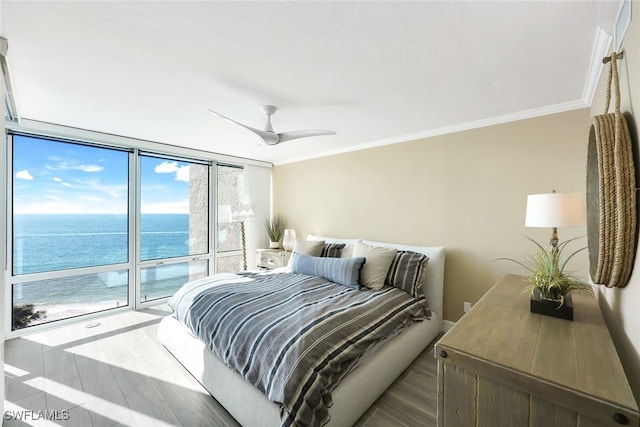 bedroom with hardwood / wood-style floors, floor to ceiling windows, a water view, crown molding, and ceiling fan