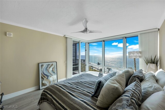 bedroom with floor to ceiling windows, a water view, crown molding, ceiling fan, and light hardwood / wood-style floors