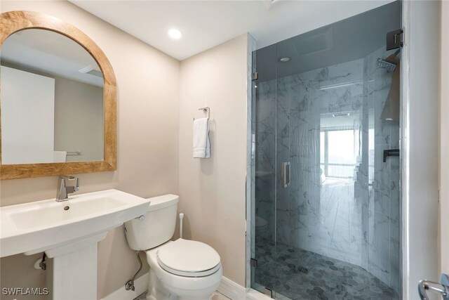 bathroom featuring a shower with shower door and toilet