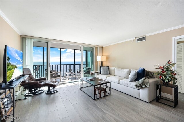 living room featuring a water view, light hardwood / wood-style flooring, a wall of windows, and crown molding