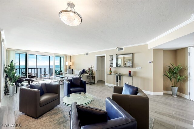 living room featuring a water view, crown molding, a textured ceiling, light hardwood / wood-style floors, and a wall of windows