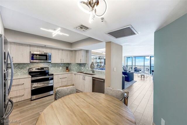 kitchen featuring sink, stainless steel appliances, tasteful backsplash, light hardwood / wood-style flooring, and light brown cabinetry