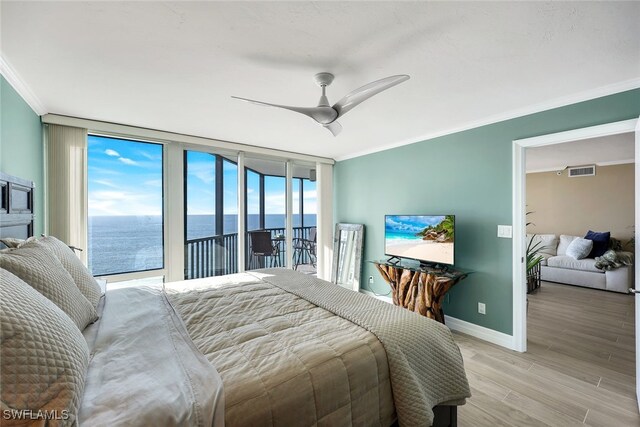 bedroom featuring access to outside, crown molding, ceiling fan, light wood-type flooring, and a wall of windows