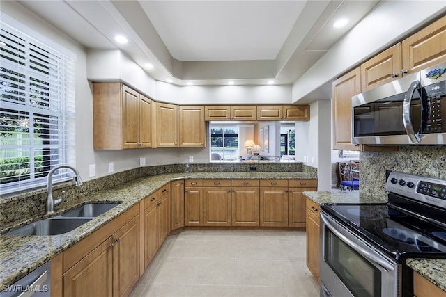 kitchen featuring stainless steel appliances, sink, light tile patterned floors, light stone counters, and tasteful backsplash