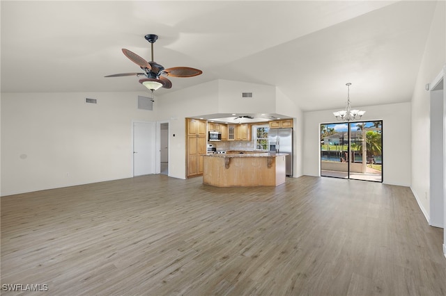 unfurnished living room with vaulted ceiling, ceiling fan with notable chandelier, and light hardwood / wood-style floors