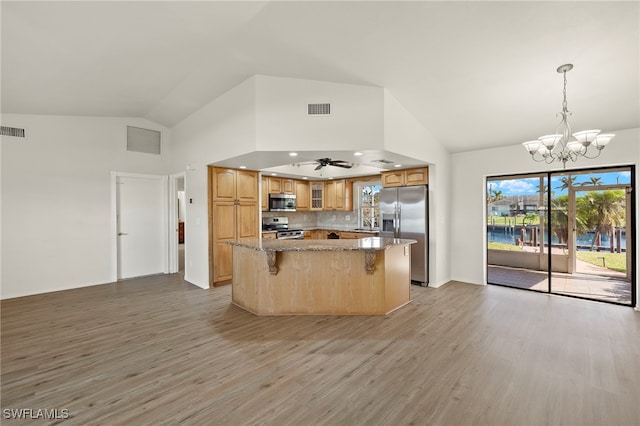 kitchen with appliances with stainless steel finishes, a center island, pendant lighting, light stone counters, and light hardwood / wood-style flooring