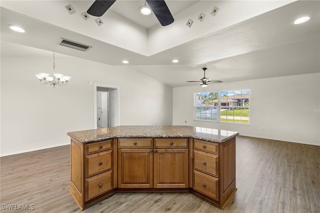 kitchen featuring lofted ceiling, light wood-type flooring, a center island, ceiling fan with notable chandelier, and decorative light fixtures