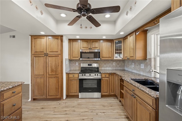 kitchen featuring sink, light stone counters, stainless steel appliances, and light wood-type flooring