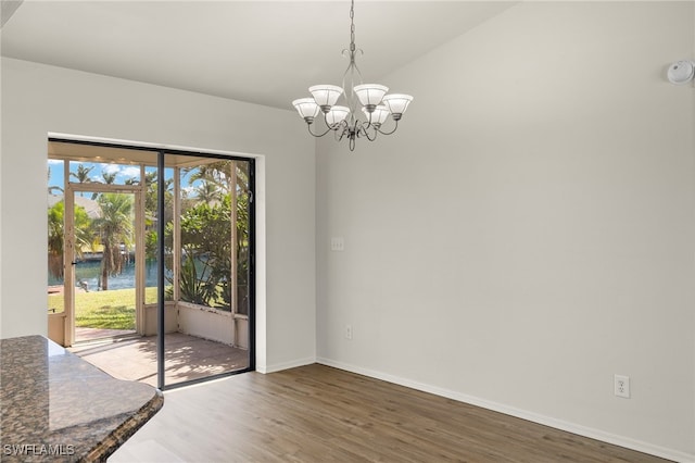 unfurnished dining area featuring an inviting chandelier, wood-type flooring, and a water view