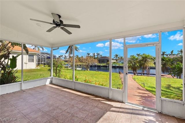 unfurnished sunroom featuring a water view, ceiling fan, a healthy amount of sunlight, and vaulted ceiling