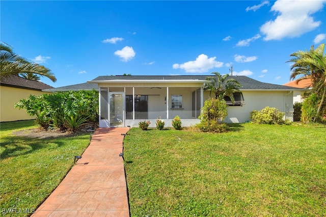 back of property with a lawn and a sunroom