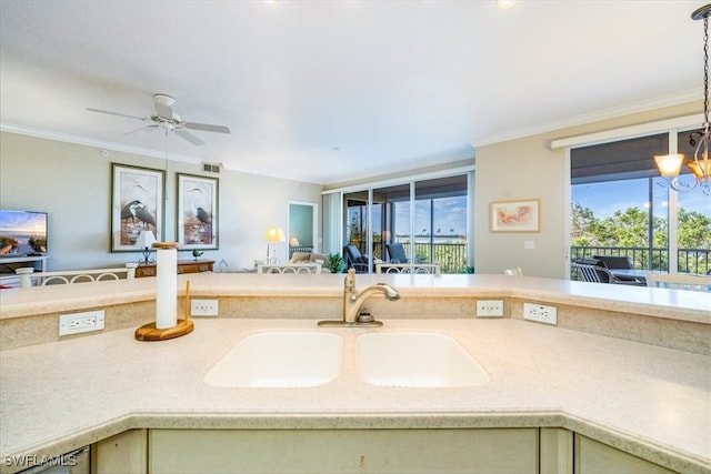 kitchen featuring cream cabinets, crown molding, sink, and ceiling fan with notable chandelier