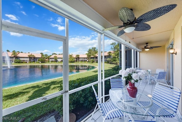 sunroom featuring a water view and ceiling fan