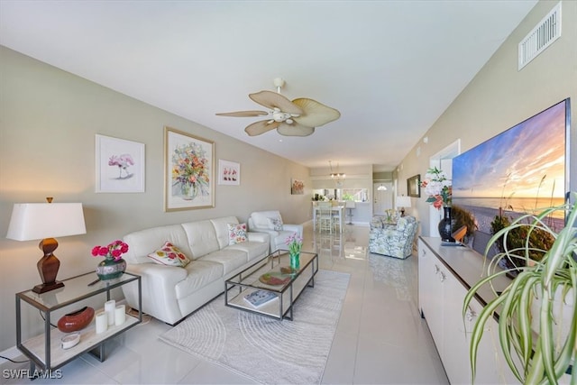 living room with ceiling fan with notable chandelier and light tile patterned floors