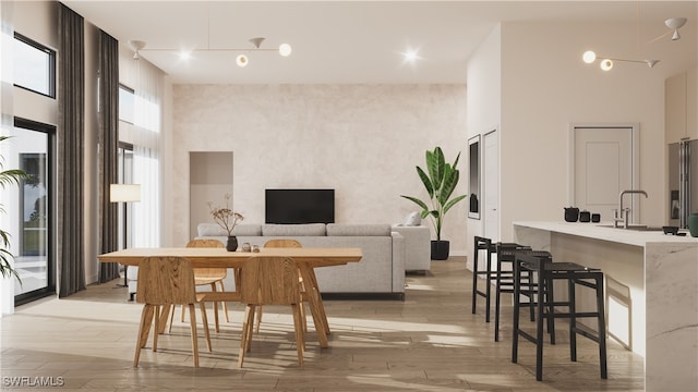 dining space featuring a high ceiling, sink, and light hardwood / wood-style flooring