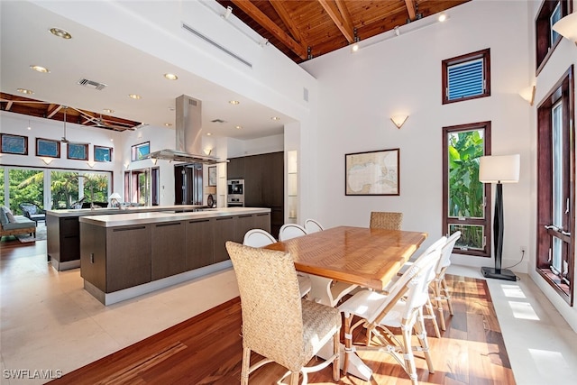 dining space with beamed ceiling, wood ceiling, light wood-type flooring, and high vaulted ceiling