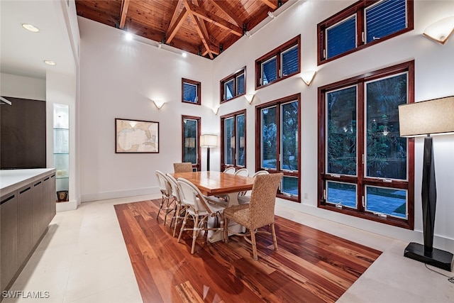 dining area featuring high vaulted ceiling, light hardwood / wood-style floors, beamed ceiling, and wooden ceiling