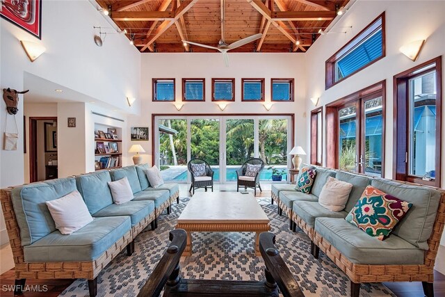 living room with a high ceiling, beamed ceiling, wood ceiling, and ceiling fan