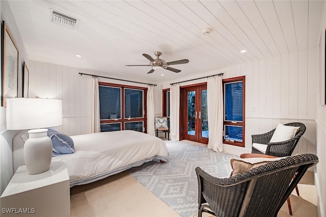 bedroom featuring wood walls, ceiling fan, access to exterior, and french doors