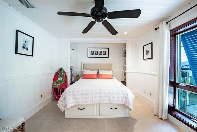 bedroom with wood walls, ceiling fan, and crown molding