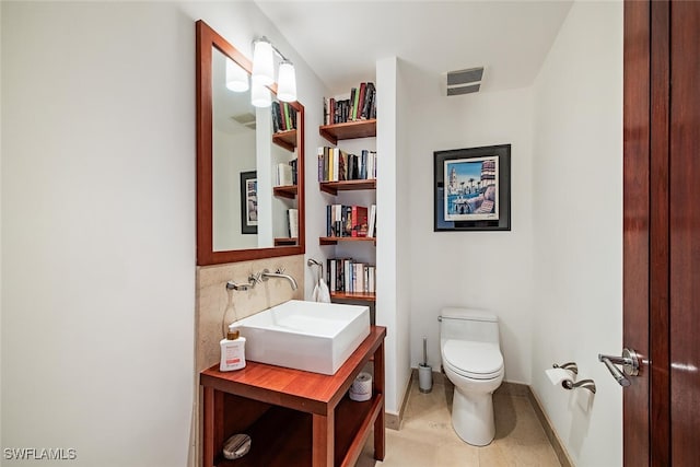 bathroom with toilet, tasteful backsplash, and sink