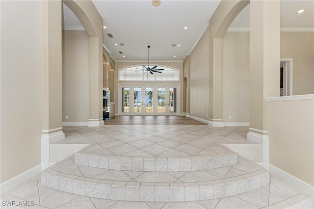 foyer entrance featuring french doors, ceiling fan, crown molding, and a fireplace