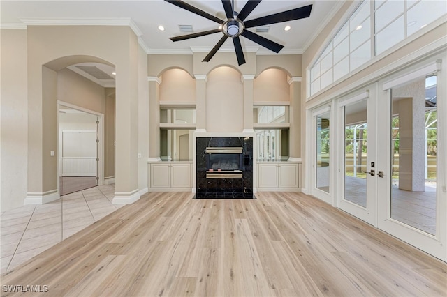 unfurnished living room featuring crown molding, light hardwood / wood-style flooring, a fireplace, and ceiling fan