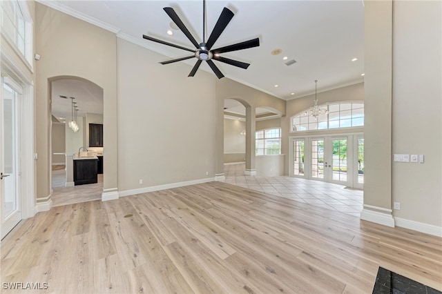 unfurnished living room with light hardwood / wood-style flooring, french doors, ceiling fan with notable chandelier, and crown molding