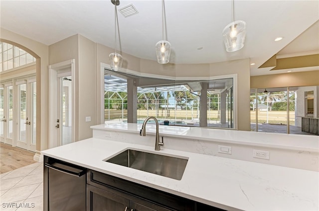 kitchen with light stone countertops, sink, hanging light fixtures, light hardwood / wood-style floors, and stainless steel dishwasher