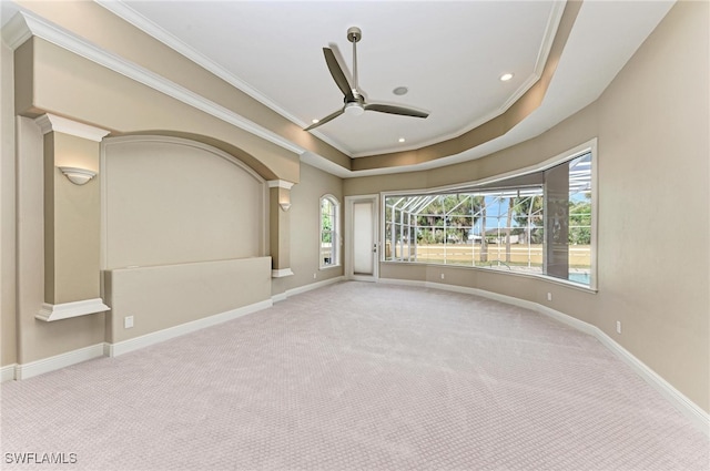 carpeted spare room with crown molding, a raised ceiling, and ceiling fan