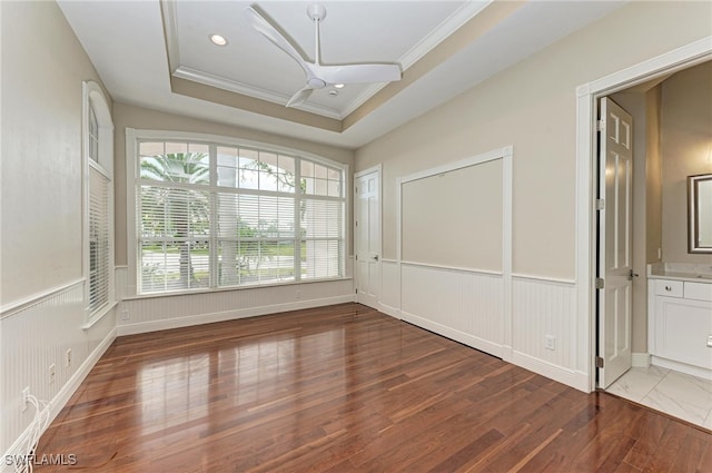 interior space featuring ceiling fan, a raised ceiling, dark hardwood / wood-style flooring, and crown molding