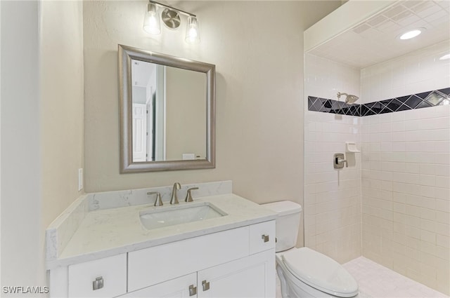 bathroom with vanity, a tile shower, and toilet