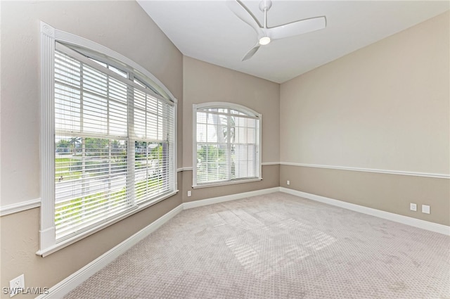 carpeted spare room featuring a wealth of natural light and ceiling fan