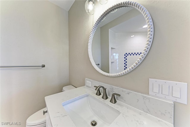 bathroom with vanity, a tile shower, and toilet