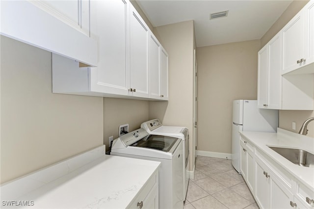 laundry area with sink, light tile patterned flooring, separate washer and dryer, and cabinets