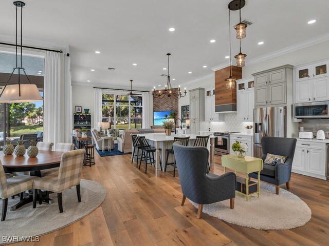 dining area with crown molding, light hardwood / wood-style floors, and a chandelier